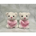 Two white teddy bears holding pink heart pillows with Mother’s Day messages