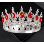 Silver jeweled crown with red teardrop stones on a black background