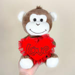 Plush monkey holding a red heart with the word love