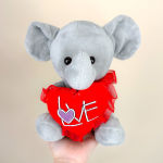 Gray plush elephant holding a red heart with the word LOVE