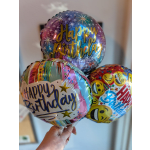 Three birthday balloons with colorful foil designs and emoji faces