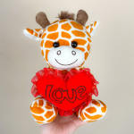 Plush giraffe holding a red heart with the word love