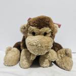 Plush monkey toy with brown and tan fur and a small ribbon bow