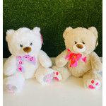 Two teddy bears with pink ribbons sitting on a white surface