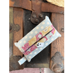 A small fabric pouch with a polka-dot and floral pattern lies on a wooden surface.