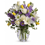 White lilies, roses, purple flowers, and yellow tulips in a glass vase