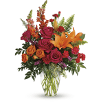 Bright mixed bouquet of roses, lilies, and carnations in a clear glass vase