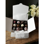 Box of assorted chocolates beside a bouquet of white roses