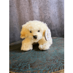 Small cream-colored plush dog with a tag sitting on a patterned surface