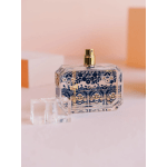 Decorative perfume bottle with a gold spray top on a pink background