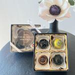 Boxed chocolates beside a single pale flower in a vase