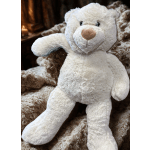 White plush teddy bear sitting on a brown patterned blanket