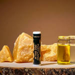 Portland Bee Balm tube beside amber crystals and small glass jars of oil