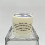 Cream-colored scented candle in a clear glass jar on a glass stand
