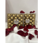 Two Ferrero Rocher chocolate boxes with red rose petals on white fabric