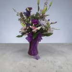 Purple and white mixed bouquet in a glass vase with a ribbon