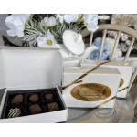 White flower arrangement with a ceramic swan and boxed chocolates