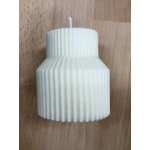 White ribbed pillar candle on a wooden surface