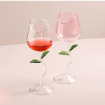 Two stemmed glass cups with pink liquid and leaf accents