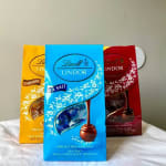 Three Lindt chocolate truffle gift boxes in yellow, blue, and red