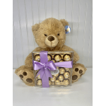 Teddy bear holding a box of Ferrero Rocher chocolates with a purple ribbon