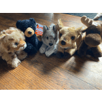 Five plush animal toys lined up on a wooden floor