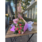 Pink tulip bouquet with white filler flowers wrapped in pink paper and ribbon on a café table