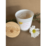 White candle in a glass jar with a wooden lid and a daisy accent