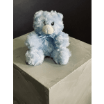 Light blue teddy bear with a satin ribbon sitting on a box