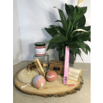 Spa gift basket with a potted green plant and bath items on a wood slab