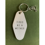 White leather keychain with the words "TIRED AS A MOTHER"