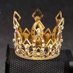 Gold jeweled crown on a black textured surface