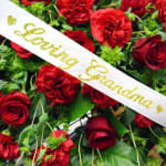 Red roses with a white ribbon reading "Loving Grandma"