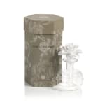 White flower-shaped perfume bottle beside a decorative box