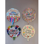 Four round birthday balloons with colorful printed designs on a wall.