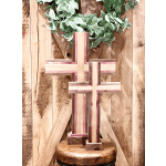 Two wooden crosses on a stool with a leafy wreath above