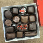 Box of assorted chocolate candies in paper cups