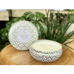Decorative lidded candle tin with three wicks on a wooden surface