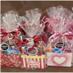 Gift baskets wrapped in clear cellophane with ribbon bows and candy assortments