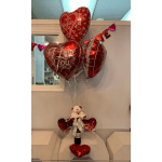 Heart-shaped Valentine balloons with a small teddy bear and wine bottle