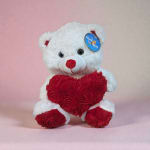 White teddy bear holding a red heart on a pink background