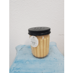 A beige candle in a glass jar with a black lid