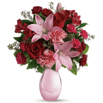 Pink lilies and red roses arranged in a pink glass vase