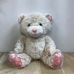 Plush teddy bear with pink accents sitting on a tiled floor