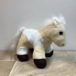 Plush toy horse with cream and white fur and dark hooves