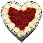 Heart-shaped black box filled with red and white roses framed by small white filler flowers