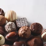 Assorted chocolate truffles and bonbons on a white surface