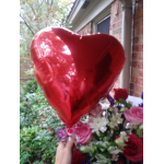 Red heart-shaped balloon above a bouquet of mixed flowers