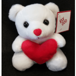 White teddy bear holding a red heart with a small tag