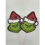 Two Grinch face picks wearing Santa hats on sticks